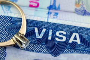 engagement ring on top of blurred us entry visa sticker in a passport