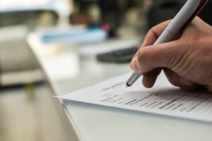 Closeup of hand writing filling job or service application form over light desk background