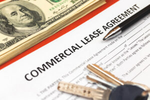 Commercial lease agreement form close-up. House keys, pen and money on office desk