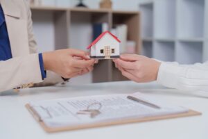 Real Estate Transaction. Handing over a miniature house model during a property deal.